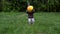 A baby girl plays with a multi-colored inflatable ball on the lawn in the park.