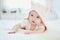 Baby girl relaxing in bedroom in pink clothes or towel with ears