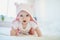 Baby girl relaxing in bedroom in pink clothes or towel with ears