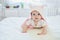 Baby girl relaxing in bedroom in pink clothes or towel with ears