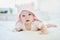 Baby girl relaxing in bedroom in pink clothes or towel with ears