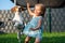 Baby girl running with beagle dog in garden on summer day. Domestic animal with children concept