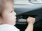 Baby girl`s hand about to pull the door handle from inside of a moving car