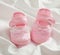 Baby girl shoes on white satin background, vertical view, copy space