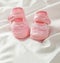 Baby girl shoes on white satin background, vertical view, copy space