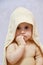 Baby girl after shower or bath with towel on head. Baby wearing hooded towel sitting on parents bed after bath or shower