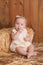 Baby Girl Sitting Against a Straw Bale