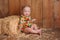 Baby Girl Sitting Against a Straw Bale