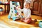 Baby girl sitting on the floor in nursery and playing with wooden push toy