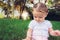 Baby girl sitting in grass in park touching playing and exploring nature - Cute kid toodler outside enjoying the summer