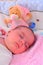 Baby girl sleeping in her bed with favorite bear toy