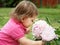 Baby girl smelling peony flowers