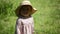 Baby girl standing on the grass in straw hat and dress, funny belly, hot weather