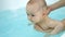 Baby girl swims in bathtub with swim teacher assistance