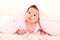 Baby girl under hidden pink blanket on white fur