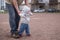 Baby girl walking outdoors with man. Granfather helping his granddaughter to walk