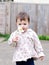 Baby girl walking in the street sniffing flower