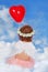 Baby girl with wings sitting on cloud with balloon