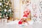 Baby girl writes a letter, and Santa Claus with a gift spies on her at the Christmas tree, the concept of new year and Christmas