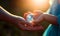 Baby hands passing the glass globe to adult\\\'s hands. Bright sunlight at backdrop. Close up. Generative AI