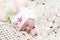 Baby in hat lies on bed under white knitted shawl