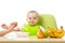 Baby having a table full of healthy food. Cheerful toddler with fruits apples, bananas, pear. Isolated on white
