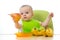 Baby having a table full of healthy fruits. Cheerful toddler holding pear. on white