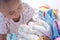 Baby with heap of colorful clothes in the room