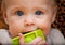 Baby holding a green block facing camera