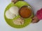 Baby Holding in Hand Home Made Indian vegetarian rice cakes breakfast known as idli or idly, served with sambar and Chatney in a