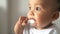 Baby holding spoon in the mouth and looking outside.Playful and lovely kid