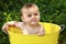 Baby with impish grin in yellow tub