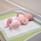 The baby infant boy lies in a diaper on the changing table in the clinic. Happy child changing clothes on nappy before appointment