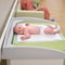 The baby infant boy lies in a diaper on the changing table in the clinic. Happy child changing clothes on nappy before appointment