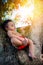 Baby infant boy six month old day dreaming reclining relaxing on tree trunk enjoying warm sunlight chilling out mixed race Caribbe