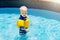 Baby with inflatable armbands in swimming pool.