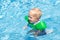 Baby with inflatable armbands in swimming pool.