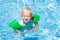 Baby with inflatable armbands in swimming pool.