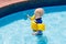 Baby with inflatable armbands in swimming pool.