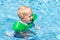 Baby with inflatable armbands in swimming pool.