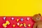 Baby kids toys background. Teddy bear, wooden car, colorful bricks on red and yellow background