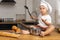 Baby in the kitchen, little cook in a white cap, mother`s assistant, baby food, family breakfasts, child plays with kitchen utensi