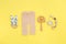 Baby knitted pants, wooden toys and soother on yellow background with copy space