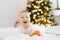 Baby laughs as he lies on the bed in the background of Christmas lights