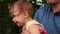 Baby laughs at hands of loving father. Baby and dad laugh, playing together for a walk in park.