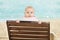 Baby Leaning On Deckchair On Beach