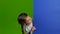 Baby looks out from behind a blue board and shows a thumbs up. Green screen