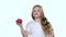 Baby looks at a tomato, admires it and shows a thumbs up. White background. Slow motion