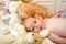 Baby lying by beige bunny. Newborn toddler with blue eyes
