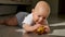 Baby is lying on the floor and holding a red apple. The child is very lively and cheerful, he actively knocks with hands